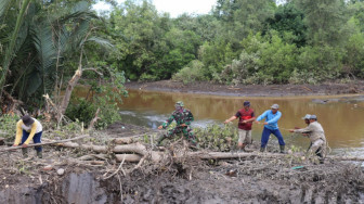 Penuh Lumpur, Anggota Satgas TMMD Bersama Warga Angkut Kayu untuk Jembatan Darurat