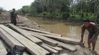 Satgas TMMD Bawa Kayu Galar Lewat Sungai