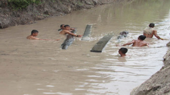 Satgas TMMD Bawa Balok Kayu Lewat Sungai